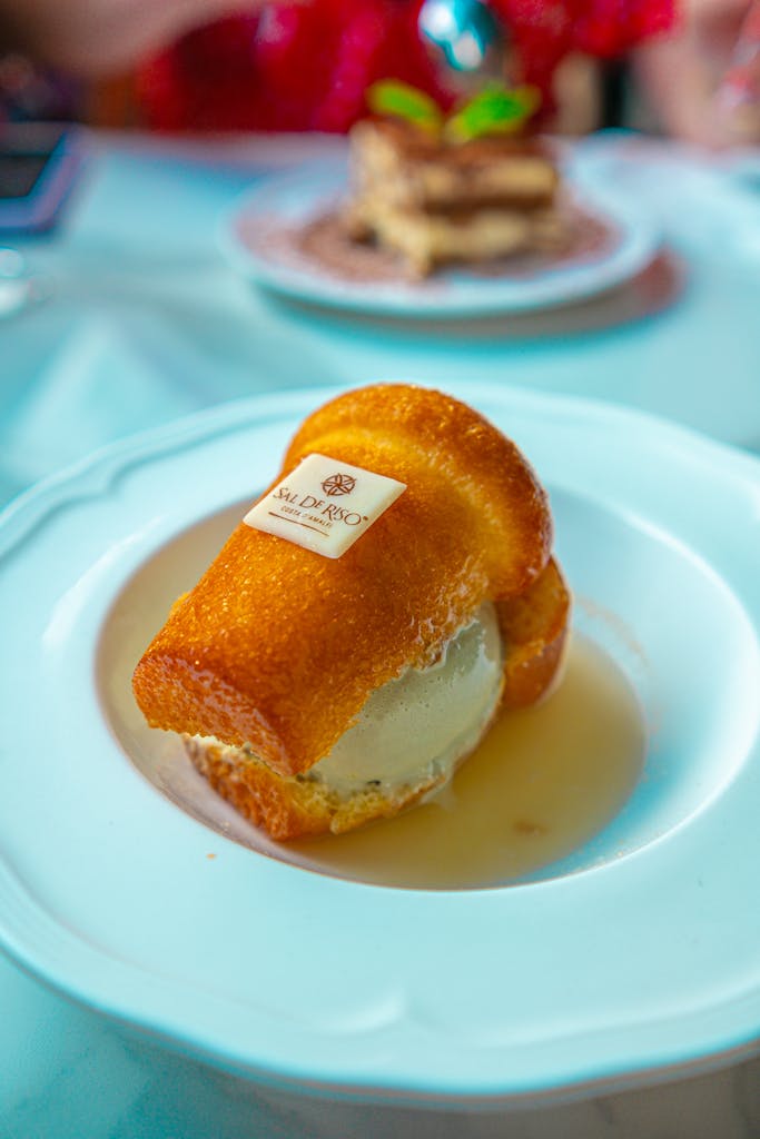 A close-up of a mouthwatering Baba au Rhum dessert served on a white plate.